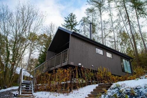 a house with a black roof in the woods at Inarden Yellowstone Cabin in Durbuy