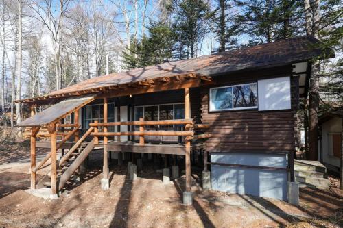 a small log cabin with a porch and a deck at アウトドアアトラクション北軽井沢 in Tsumagoi