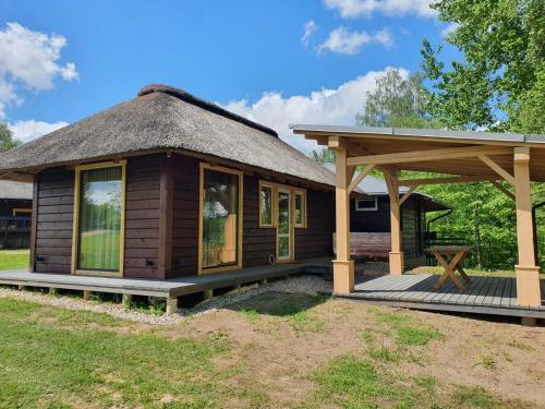 a small wooden cabin with a thatched roof at Viesu Sēta LOCU SALA in Krāslava