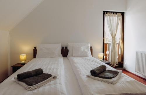 a large white bed with two pillows on it at Pensiunea Csató Borzont - Csató Panzió Borzont in Borzont