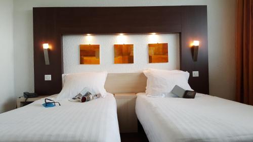 two beds in a hotel room with white sheets at Hôtel Windsor Contact Hôtel in Dieppe