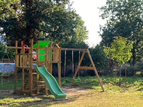 a wooden playground with a green slide and a swing at Résidence Thibaud in Toulouse