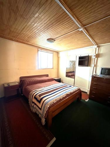 Un dormitorio con una cama y un televisor. en Casa cabaña en Playa Cocholgue, Tomé, Concepción, en Tomé