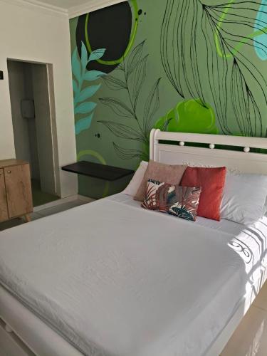 a bedroom with a white bed with plants on the wall at Hospedaje Rosa Blanca in Cartagena de Indias