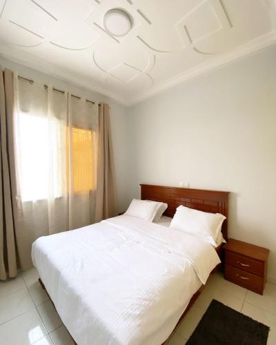 a bedroom with a large white bed and a window at Luma in Yaoundé