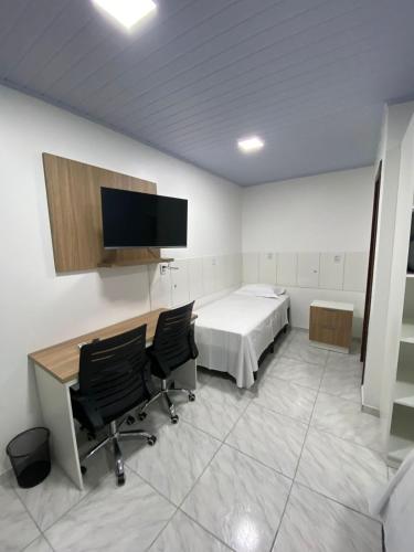 a room with a bed and a desk and two chairs at Pousada Route 58 in Gravataí