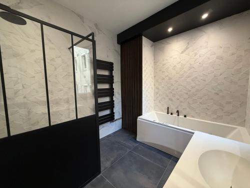 a bathroom with a bath tub and a sink at Suite Marguerite - Haussmannien chic hyper centre in Angers