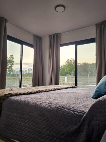 a bedroom with a large bed and large windows at Elysium de Uco in Tupungato