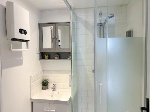 une salle de bain blanche avec un lavabo et une douche dans l'établissement Appart 4pers RDC 2Chambres près Paris, Orly, Disney, à Saint-Pierre-du-Perray