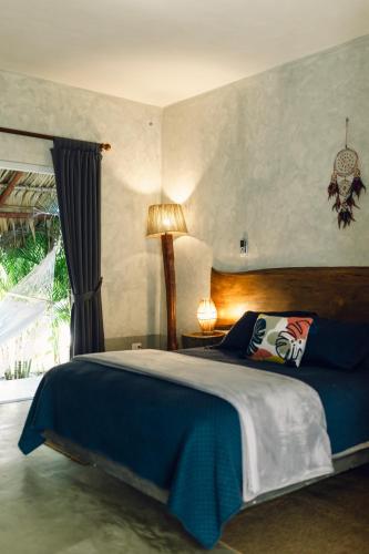a bedroom with a large bed with a blue blanket at Ka´ana Surf in El Paredón Buena Vista