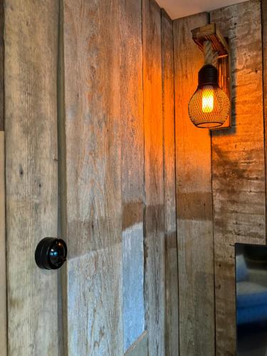 a light on a wall with a wooden wall at Cosy Hideaway 7 min from Soho farmhouse in Enstone