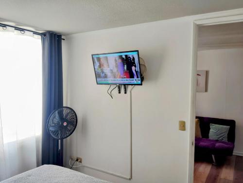サンティアゴにあるAlojamiento Santiago Centro Chileの壁にテレビとファンが備わる客室です。