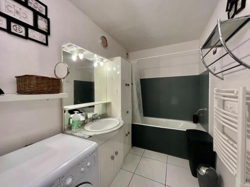 La salle de bains blanche est pourvue d'un lavabo et d'une baignoire. dans l'établissement Le Cosy Blanchepierre, bel appartement classé 3 étoiles, à Gérardmer