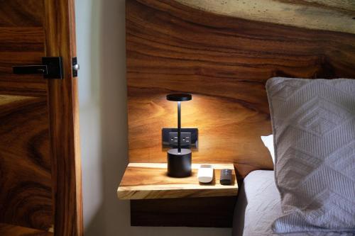 a bed with a wooden head board with a lamp on a night stand at Wabi Sabi Sora in Punta Uva