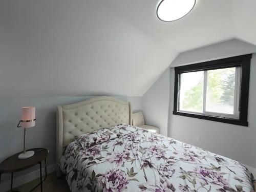 a bedroom with a bed with a floral bedspread and a window at The Luxe Escape Calgary I 3BR Vacation Home in Calgary
