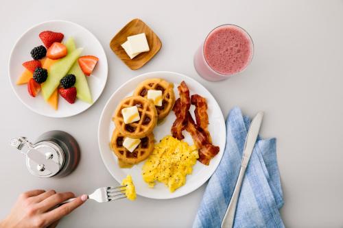 a table topped with plates of breakfast foods and a person holding a fork at Hampton Inn by Hilton Costa Mesa Newport Beach in Costa Mesa