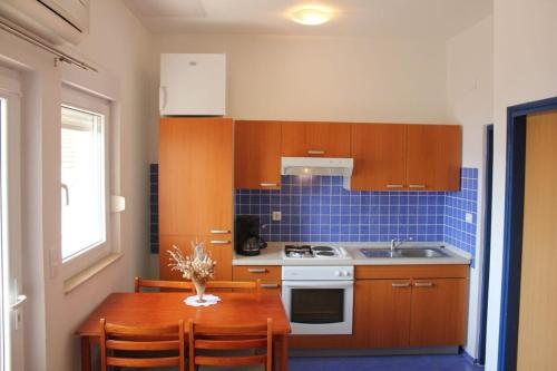 una cucina con un tavolo di legno e una cucina con piastrelle blu di Apartments Ante a Posedarje (Possedaria)