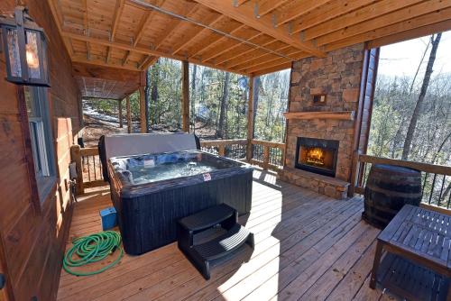 a large hot tub on a deck with a fireplace at Stoneman Lodge | Cherry Log in Cherry Log