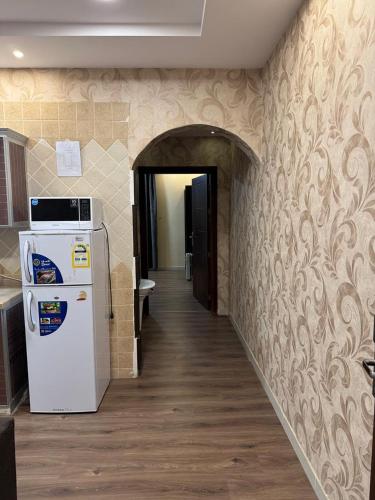a kitchen with a white refrigerator in a hallway at Oroub El Forssan in Buraydah