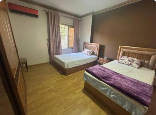 a bedroom with two beds and a window at The GEM Star House in Cairo