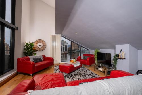 a living room with red furniture and a large window at Luxury 5-Bed Penthouse with Free Parking & Views in Belfast
