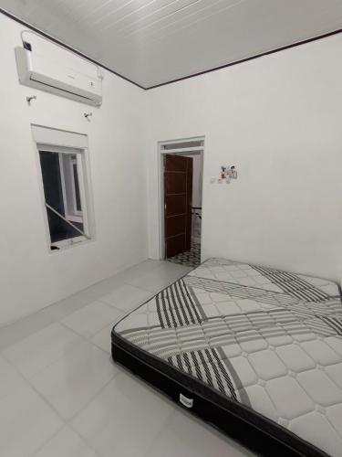 Una habitación blanca con una cama en el medio. en Guest house manggis11 Alam Asri, en Cirebon