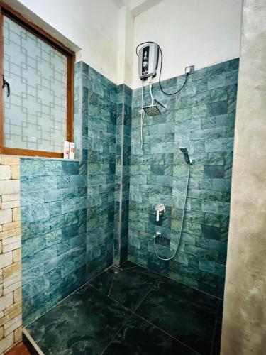 a bathroom with a shower with blue tiles at Nivartana Villa and Purana Ayurveda Center in Bentota