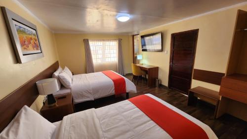 una camera d'albergo con due letti e una scrivania di INCA PALACE EXPERIENCE Hotel a Puno