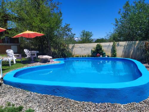 a swimming pool in a yard with an umbrella at Cabaña con piscina compartida in Mina Clavero