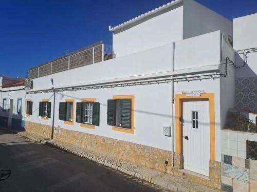 a white building with a door and windows at Linas Guesthouse in Parchal