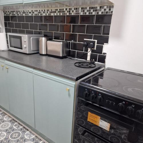 a kitchen with a stove and a microwave at Balco Strata Studio in Nottingham