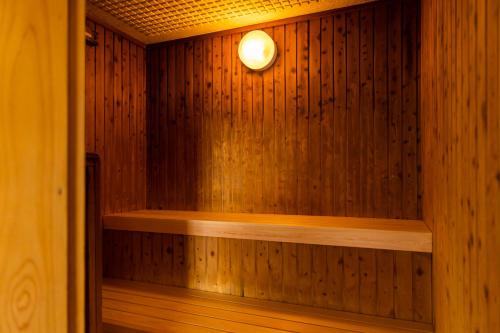 a sauna with a light on a wooden wall at Natural Hot Spring Ariston Hotel Oita in Oita
