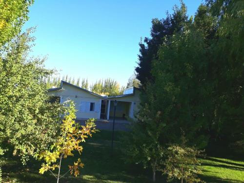 a white house with trees in front of it at Cabañas EL BOSQUE in Malargüe