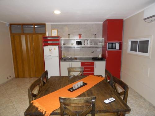 a kitchen with a wooden table and a red refrigerator at Cabañas EL BOSQUE in Malargüe