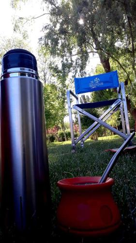 a thermos and a blue chair in the grass at Cabañas EL BOSQUE in Malargüe