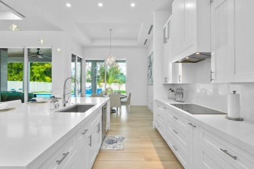a white kitchen with white cabinets and a dining room at Blue Diamond Beach Home in Bonita Springs