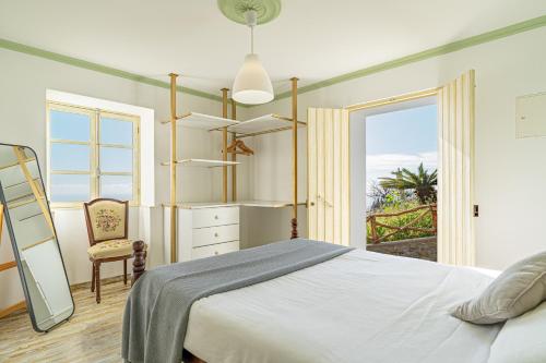 a bedroom with a bed and a chair and a window at Vila Pitaias in Estreito da Calheta