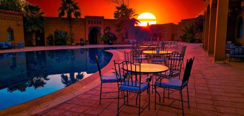 a group of tables and chairs next to a pool at Palm's Hotel Club in Erfoud