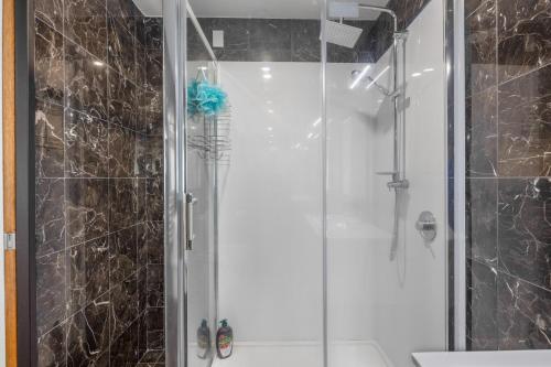 a shower with a glass door in a bathroom at The Ultimate Deck House in One Tree Point