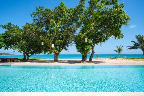 a pool with trees and the beach in the background at Yatule Resort & Spa in Natadola