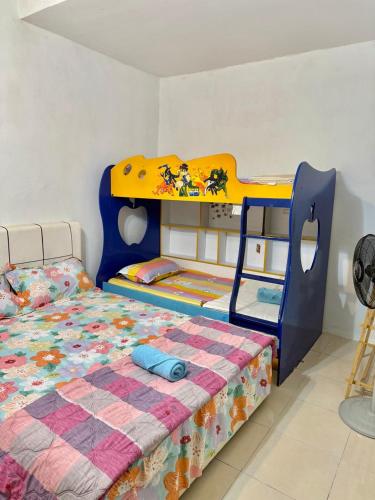 a childs bedroom with a bunk bed and a bed with a blanket at iLham Homestay in Kangar