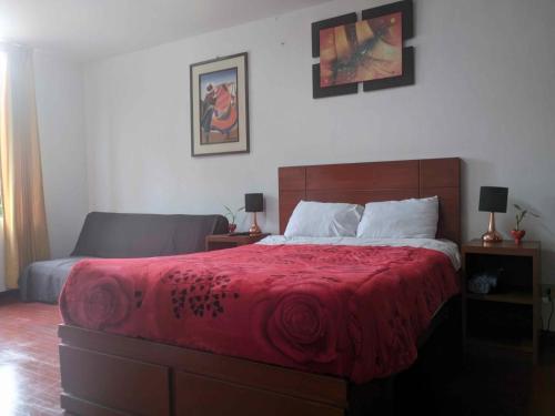 a bedroom with a large bed with a red blanket at Sumaq Wasi Caminos Del Inca in Lima