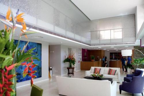 a lobby with white furniture and a large painting on the wall at Amplio PH en Margarita Real in Pampatar