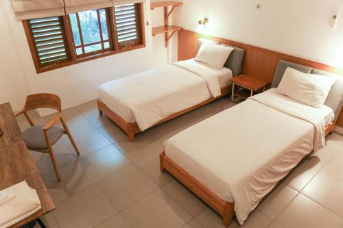 a bedroom with two beds and a table and a chair at Djajanti House in Semarang