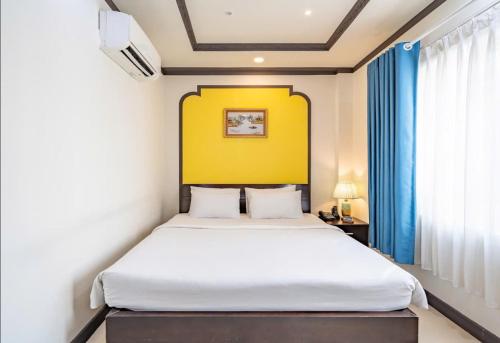 a bedroom with a large bed with a yellow wall at La Serena Boutique Hotel in Ho Chi Minh City