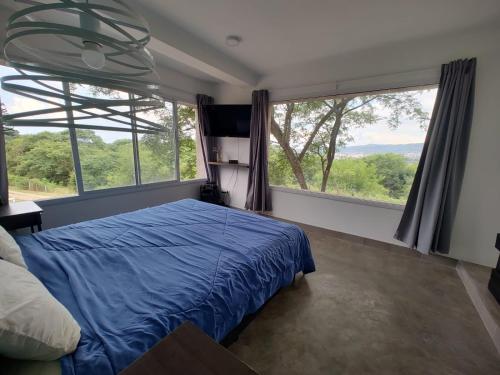 ein Schlafzimmer mit einem blauen Bett und großen Fenstern in der Unterkunft Casa Bella Vista in San Salvador de Jujuy