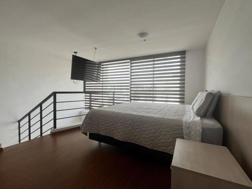 a bedroom with a bed and a large window at Espectacular Loft en UIO in Quito