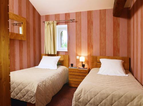 two beds in a room with striped walls at B&B Domaine de La Corbe in Bournezeau