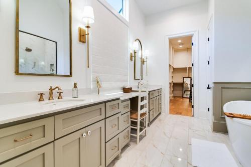 ein weißes Badezimmer mit zwei Waschbecken und einer Toilette in der Unterkunft Cajun Country Retreat King Beds Patio Arcade Luxe in Lafayette