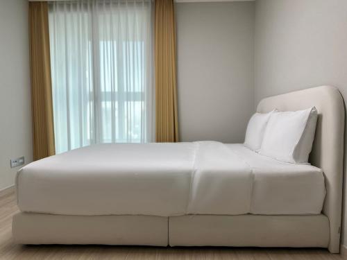 a white bed in a room with a window at The November Stay Guri Station in Guri